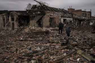 Residents walk on the rubble of destroyed buildings in the town of Trostsyanets.