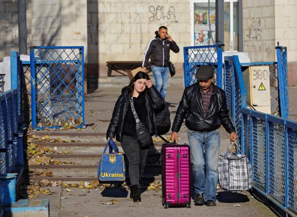 People walk to board a ferry during the evacuation of civilians from Kherson